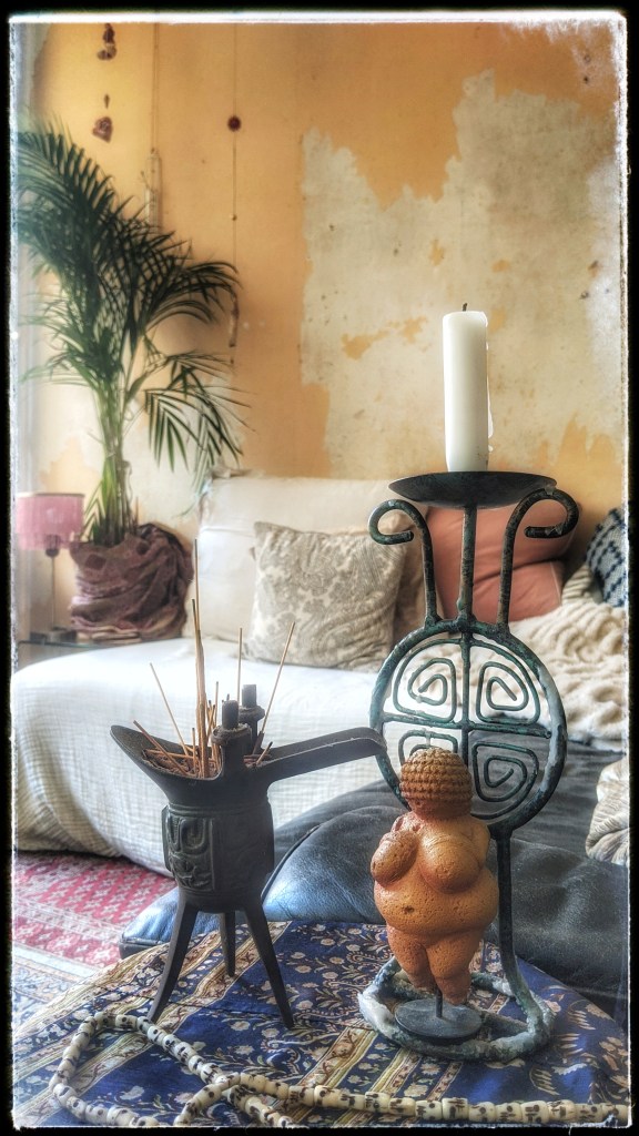 a photo candles in the foreground and two couches, cushions and a green plant in the background